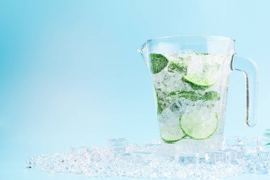 Açık mavi arka planda mojito kokteyli olan büyük bir sürahi. Yaz sıcağında meşrubat kavramı.