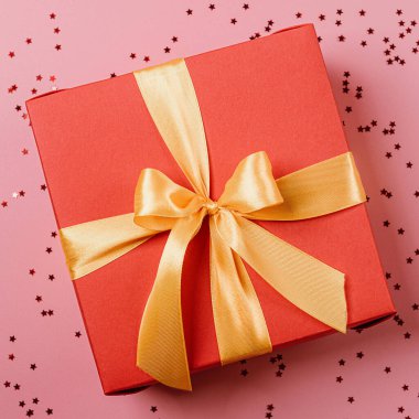 Altın kurdeleyle bağlanmış kırmızı hediye kutusu. Kurdele bir kutunun üzerinde fiyonkla bağlanmış. hediye konsepti