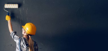 Kadın duvarı boyuyor.