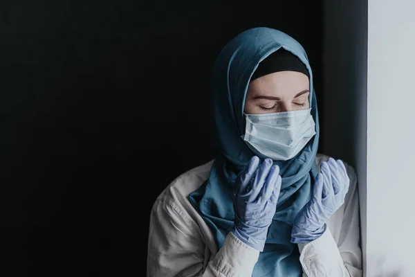 Çok sayıda hasta aldıktan sonra koronavirüs salgını nedeniyle dua eden yorgun doktor kadın müslüman kadın.