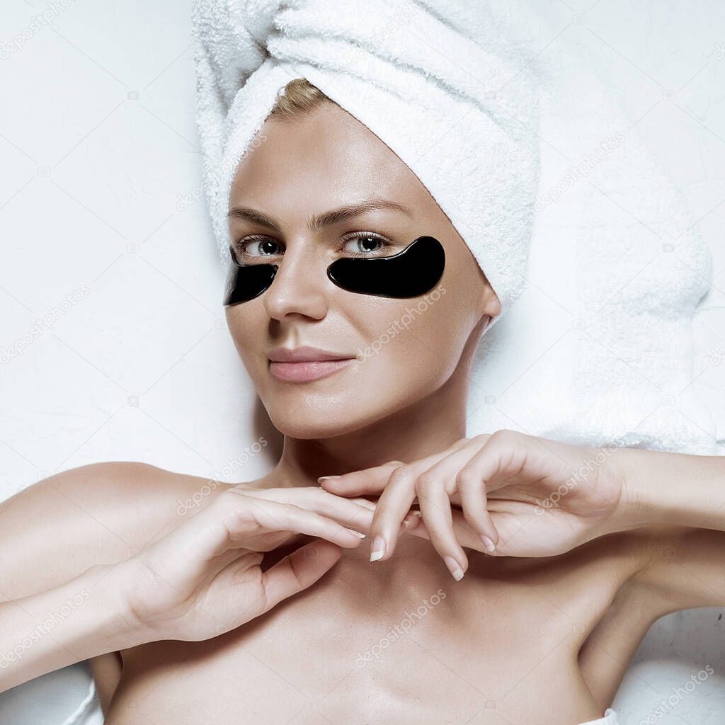 cosmetic mask for the skin under the eyes. patch eye mask on a girl with a towel on her head