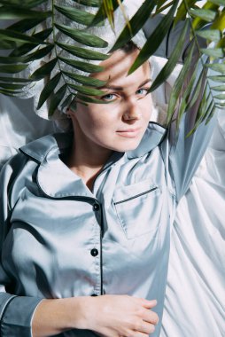 Pijamalı ve kafasında havluyla sabah güneşinin parladığı pencereden yatağa uzanmış bir kadın, rahatlamış ve huzurlu.