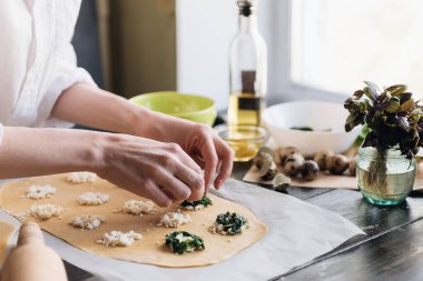 Aşçı adım adım ricotta peynirli ravioli, bıldırcın yumurtası ve baharatlı ıspanak hazırlar. Şef hamurun içini doldurur.