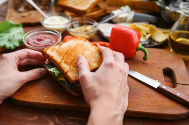 Ev sahibesi misafirler için ahşap bir masada sandviç hazırlar.