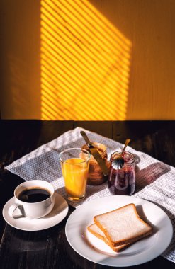 Fıstık ezmesi ve reçelli kahvaltı ve sabah güneşinde bir fincan kahve.