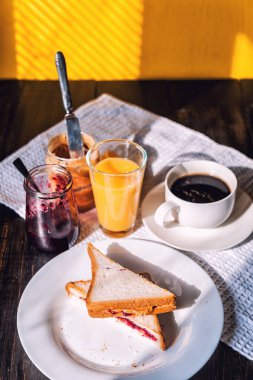 Fıstık ezmesi ve reçelli kahvaltı ve sabah güneşinde bir fincan kahve.