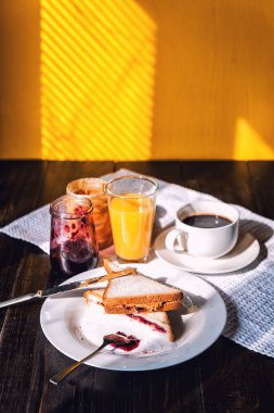 Fıstık ezmesi ve reçelli kahvaltı ve sabah güneşinde bir fincan kahve.