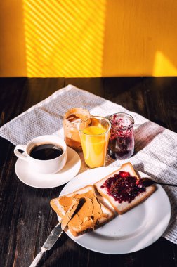 Fıstık ezmesi ve reçelli kahvaltı ve sabah güneşinde bir fincan kahve.