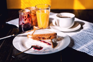 Fıstık ezmesi ve reçelli kahvaltı ve sabah güneşinde bir fincan kahve.