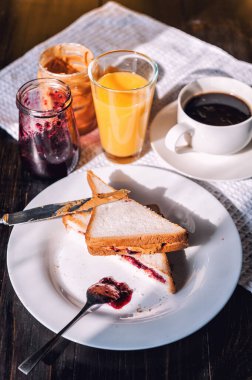 Fıstık ezmesi ve reçelli kahvaltı ve sabah güneşinde bir fincan kahve.