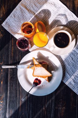 Fıstık ezmesi ve reçelli kahvaltı ve sabah güneşinde bir fincan kahve.