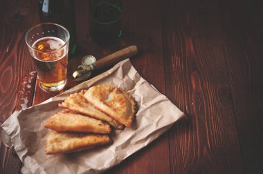 Ahşap bir arka planda biralı cheburekler. Börekler