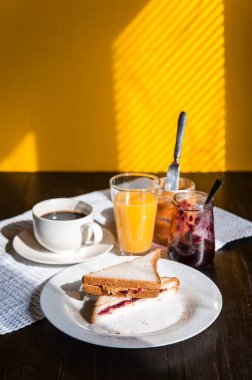 Fıstık ezmesi ve reçelli kahvaltı ve sabah güneşinde bir fincan kahve.