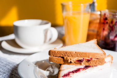 Fıstık ezmesi ve reçelli kahvaltı ve sabah güneşinde bir fincan kahve.