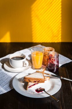 Fıstık ezmesi ve reçelli kahvaltı ve sabah güneşinde bir fincan kahve.