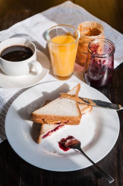 Fıstık ezmesi ve reçelli kahvaltı ve sabah güneşinde bir fincan kahve.