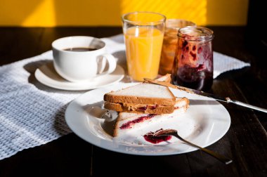 Fıstık ezmesi ve reçelli kahvaltı ve sabah güneşinde bir fincan kahve.