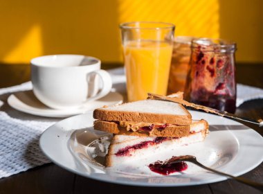Fıstık ezmesi ve reçelli kahvaltı ve sabah güneşinde bir fincan kahve.
