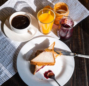 Fıstık ezmesi ve reçelli kahvaltı ve sabah güneşinde bir fincan kahve.