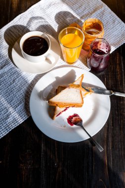 Fıstık ezmesi ve reçelli kahvaltı ve sabah güneşinde bir fincan kahve.