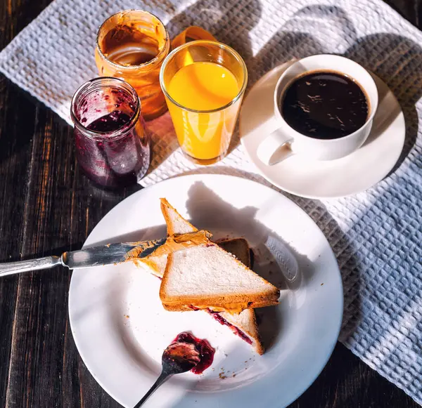 Fıstık ezmesi ve reçelli kahvaltı ve sabah güneşinde bir fincan kahve.