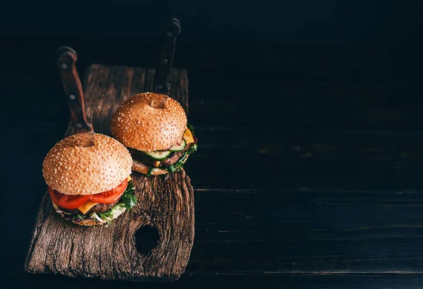 İki ağız sulandırıcı, nefis ev yapımı burger sığır eti doğramak için kullanılır. Tahta masada. Hamburgerler yerleştirilmiş bıçaklar..