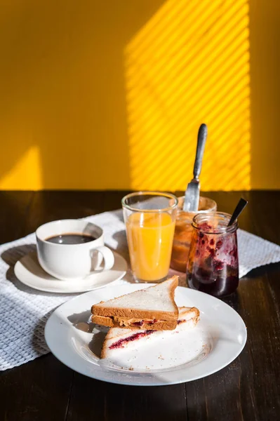 Fıstık ezmesi ve reçelli kahvaltı ve sabah güneşinde bir fincan kahve.