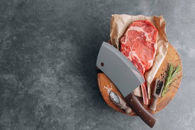 Et için ahşap bir blokta taze çiğ tamahawk bifteği ya da et için kasap baltası olan kovboy bifteği yanında kekik ile öğütülmüş biber ve kaba tuz karışımı var. taze biftek.