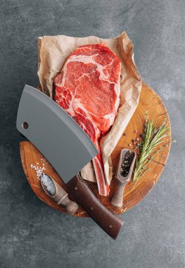 Et için ahşap bir blokta taze çiğ tamahawk bifteği ya da et için kasap baltası olan kovboy bifteği yanında kekik ile öğütülmüş biber ve kaba tuz karışımı var. taze biftek.