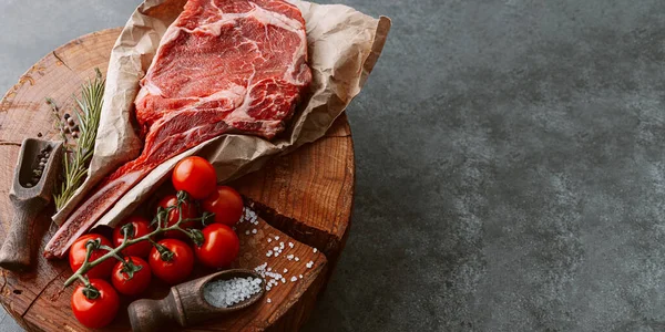 Taze çiğ kovboy baltası bifteği et için ahşap bir kesme tahtasının üzerinde