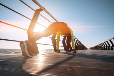 Açık hava sporu konsepti. Eşofmanlı genç kadın iskelede spor yapıyor.