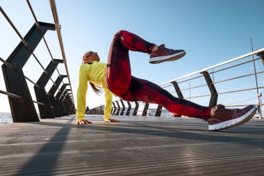 Açık hava sporu konsepti. Eşofmanlı genç kadın iskelede spor yapıyor.
