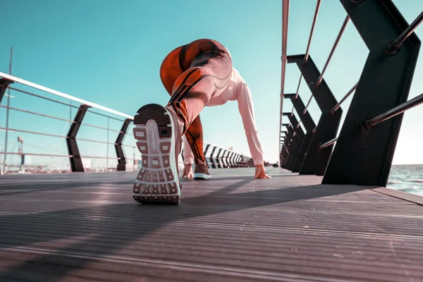 Açık hava sporu konsepti. Eşofmanlı genç kadın iskelede spor yapıyor.