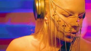 Avrupalı havalı bir bayan DJ, sarı saçlı ve Hıristiyan haçlarından yapılmış şık bir maske, bir gece kulübünde çalışıyor ve dans müziği yaratıyor..