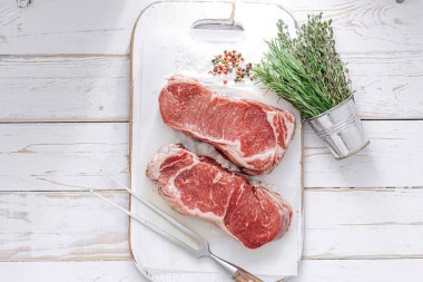 Beyaz ahşap bir tahtada taze çiğ biftek ahşap bir zemin üzerinde tuz ve biberle kırsal bir tarzda..