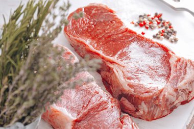 Beyaz ahşap bir tahtada taze çiğ biftek ahşap bir zemin üzerinde tuz ve biberle kırsal bir tarzda..