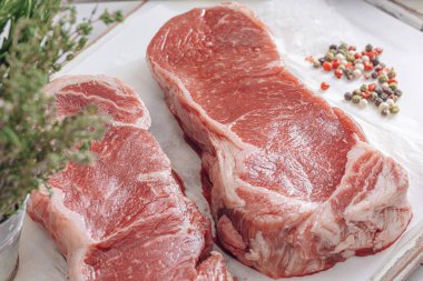 Beyaz ahşap bir tahtada taze çiğ biftek ahşap bir zemin üzerinde tuz ve biberle kırsal bir tarzda..