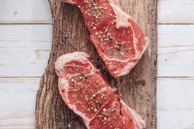 Beyaz ahşap bir tahtada taze çiğ biftek ahşap bir zemin üzerinde tuz ve biberle kırsal bir tarzda..