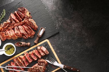İki biftek striploin ve t-bon, orta pişmiş, taş bir arka planda. İki kişilik akşam yemeği.