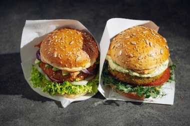 Glütensiz ve etsiz iki taze vejetaryen burger. Gri taştan bir arka planda hamburger. Lokantada ya da kafede hamburger servis ediyorlar.
