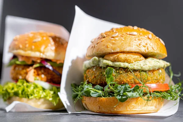 vegetarian, vegan burger with whole wheat buns, tomatoes, onions, vegan mayonnaise and spinach on a fresh bun with flaxseed and sesame seeds, surrounded by spinach leaves.