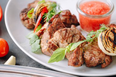 Şiş kebap ve sebze ızgara ve beyaz tabakta servis edilir.