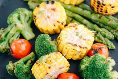 Kızarmış sebze, mısır, domates, brokoli ve kuşkonmaz.