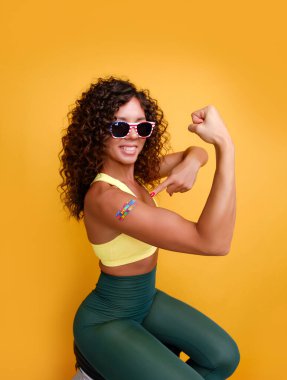 Koyu tenli, mutlu yüzlü, kolunda alçı olan bir kadın. Kovid aşısı olduğu yerde. Aşı olduktan sonra gülümsüyor.