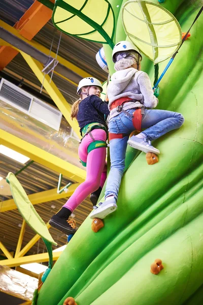 Two athlete girls climbing on artifical green tree — Stockfoto