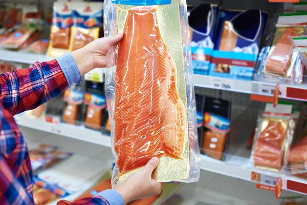 Vrouw koopt in de supermarkt gezouten zalm — Stockfoto