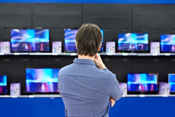 Hombre mira los televisores LCD en la tienda —  Fotos de Stock