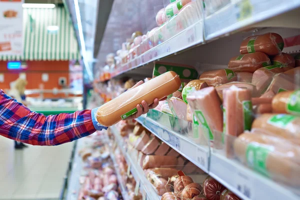 Woman chooses sausages in store — Stock Photo, Image