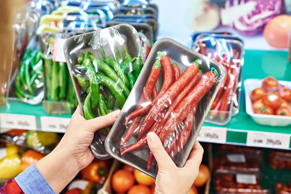 Koper selecteert chilipepertjes in winkel — Stockfoto