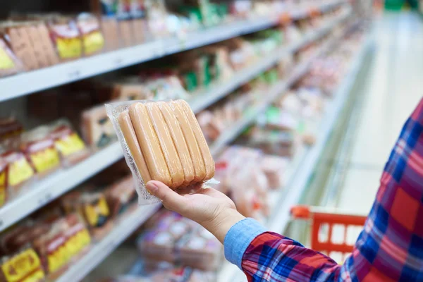 Woman chooses sausages in store